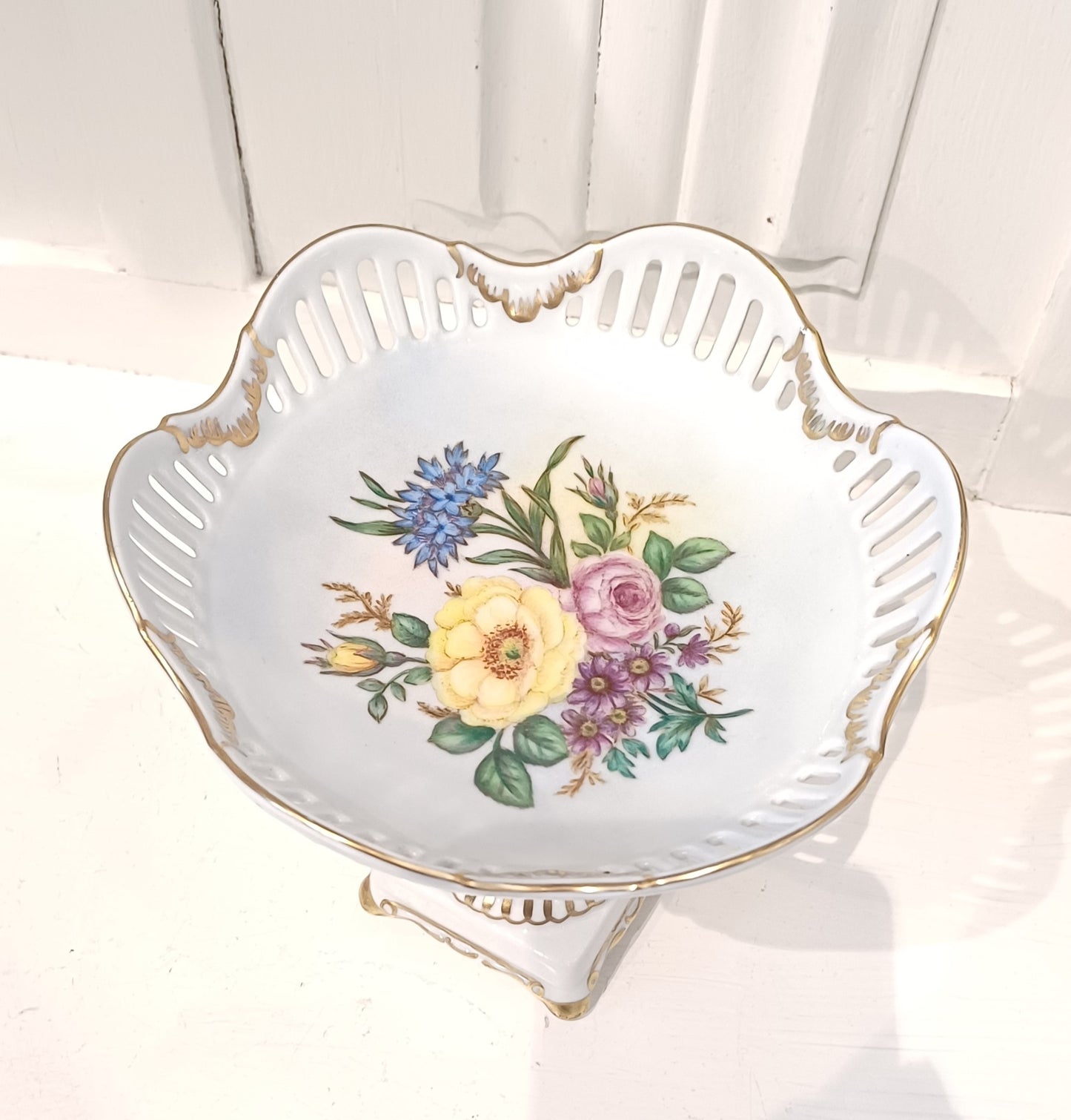 Porcelænsopsats med hulmønster, blomstermotiv og gulddetaljer.