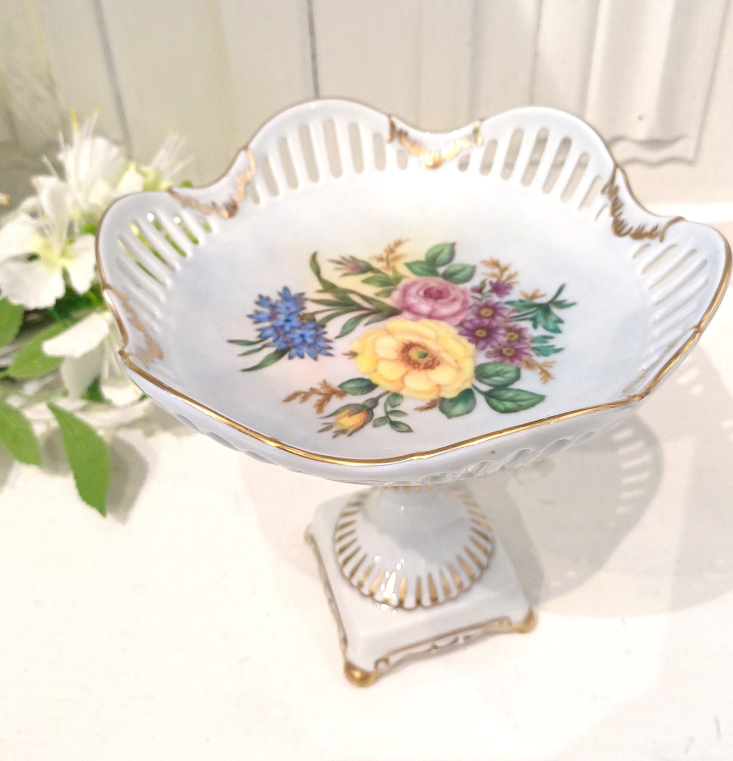 Porcelænsopsats med hulmønster, blomstermotiv og gulddetaljer.