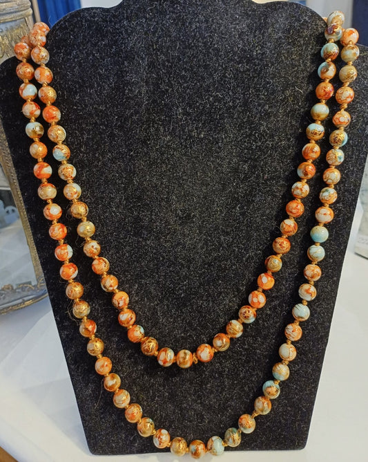 Langt lyseblå og brune perlehalskæde med guldtråd.