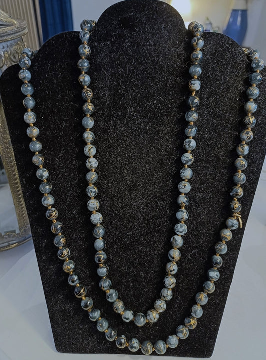 Langt eksklusivt sort perlehalskæde med guldtråde.