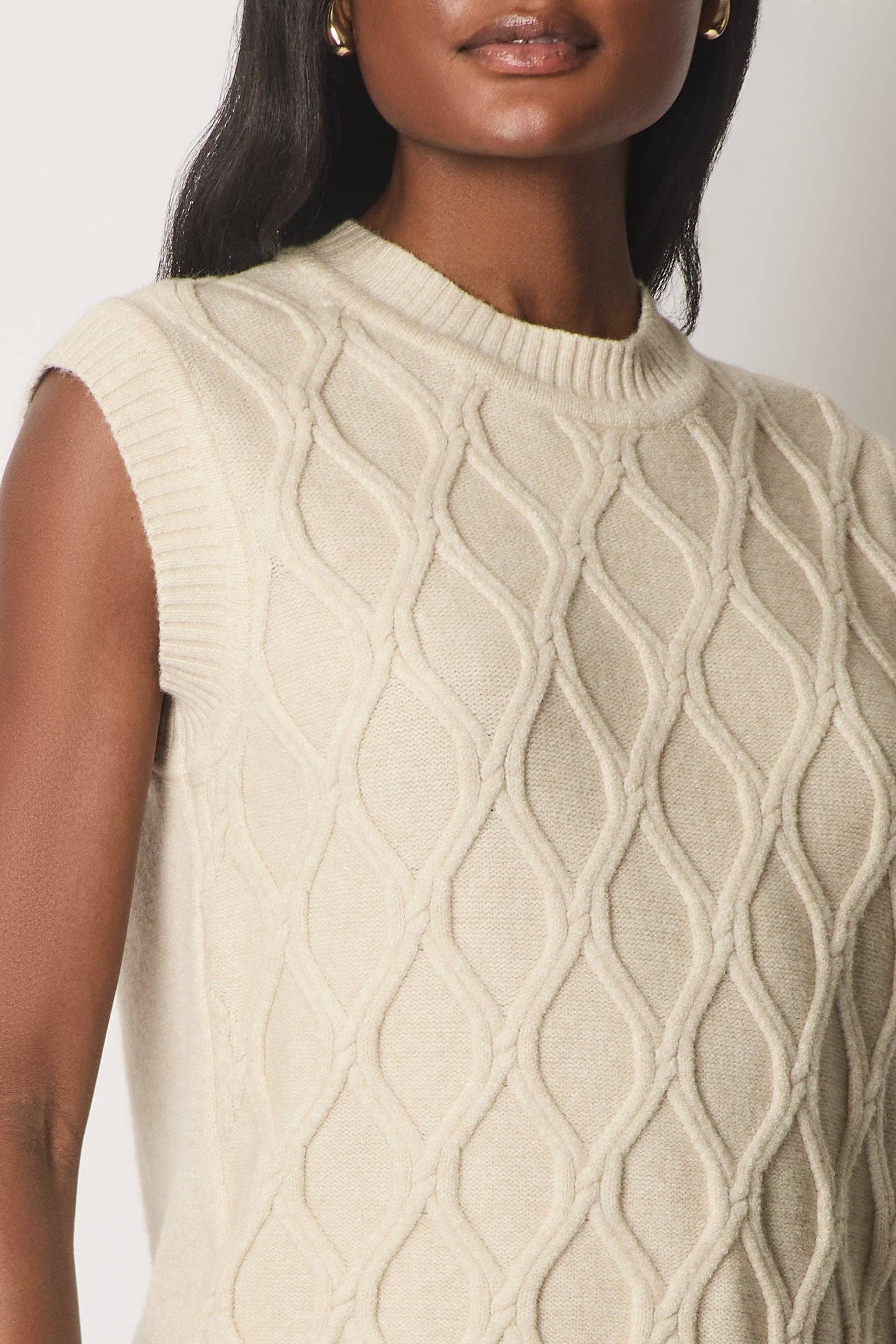 Ærmeløs kabelstrikket jumper.