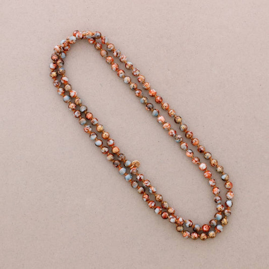 Langt lyseblå og brune perlehalskæde med guldtråd.