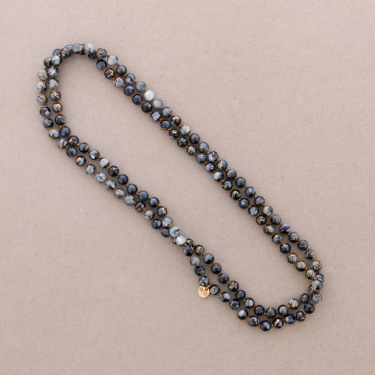 Langt eksklusivt sort perlehalskæde med guldtråde.