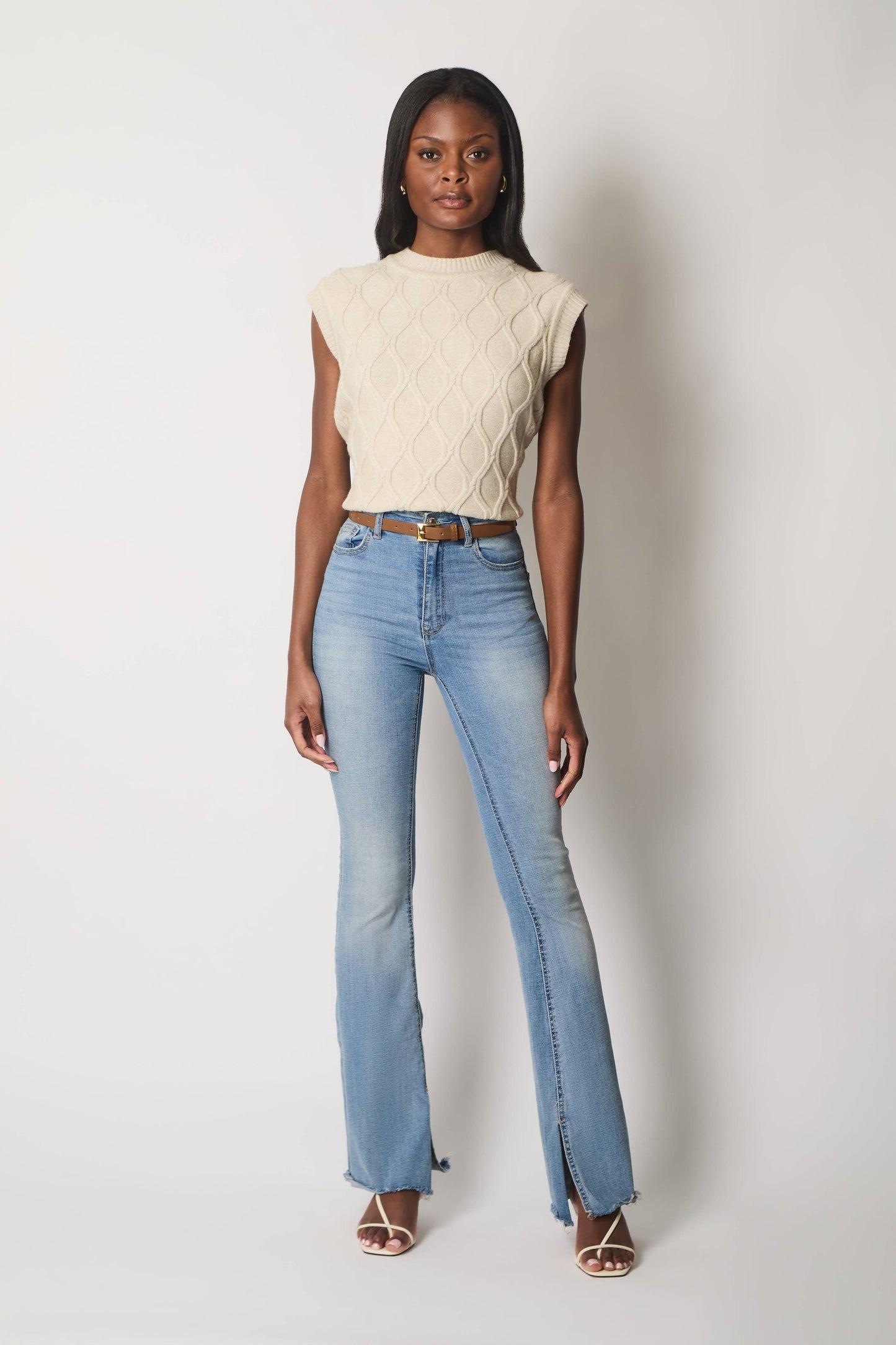 Ærmeløs kabelstrikket jumper.